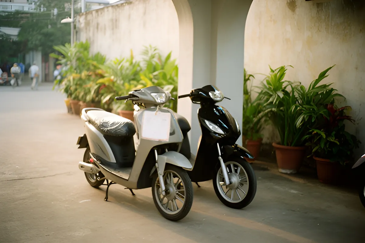 Sân nhà rộng vắng người, hai xe máy điện đậu cạnh nhau cạnh hàng chậu cây, ánh chiều dịu